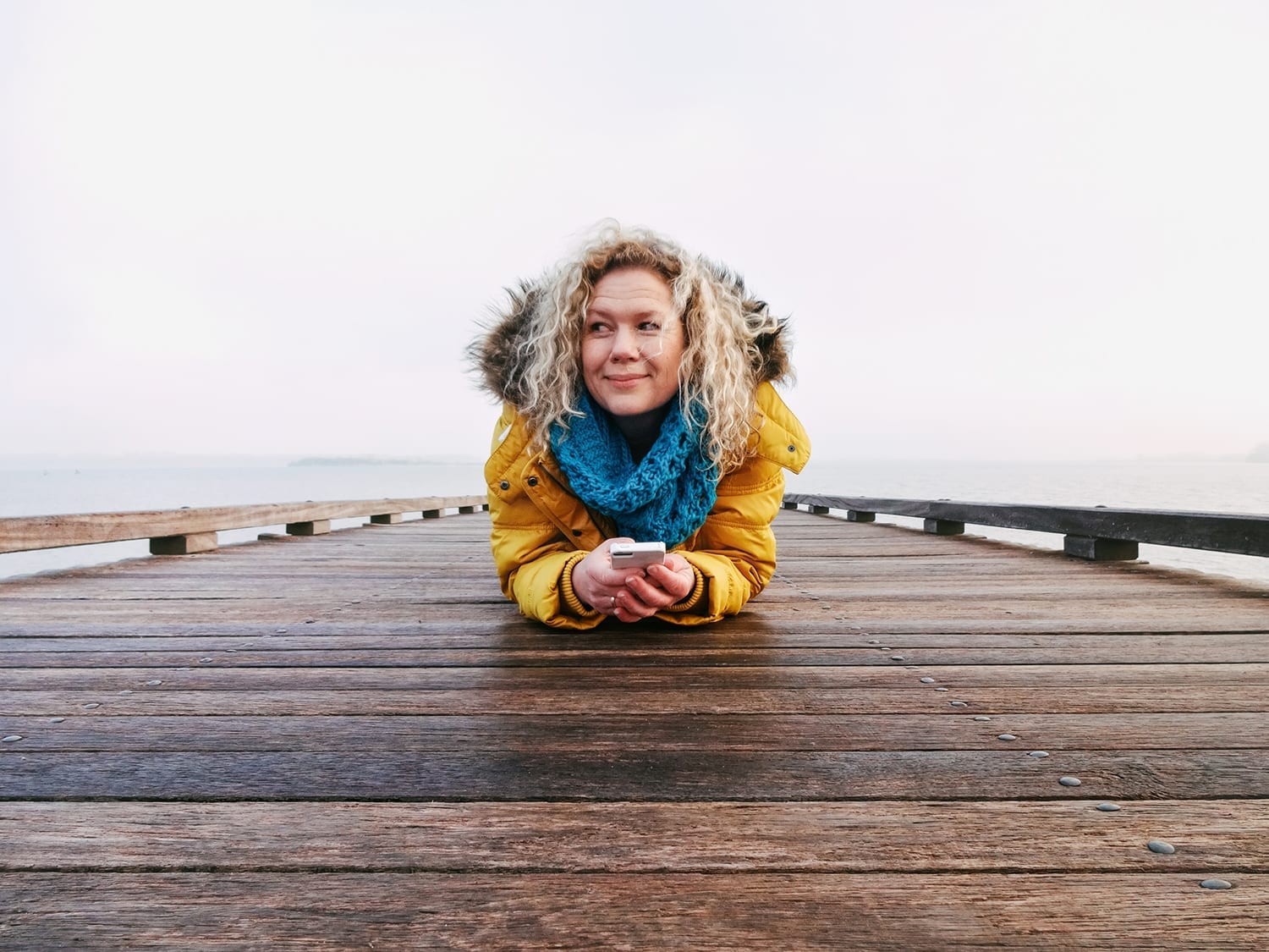 Self portret van marianne hope op een pier in huizen Nederland vrouw met gele jas