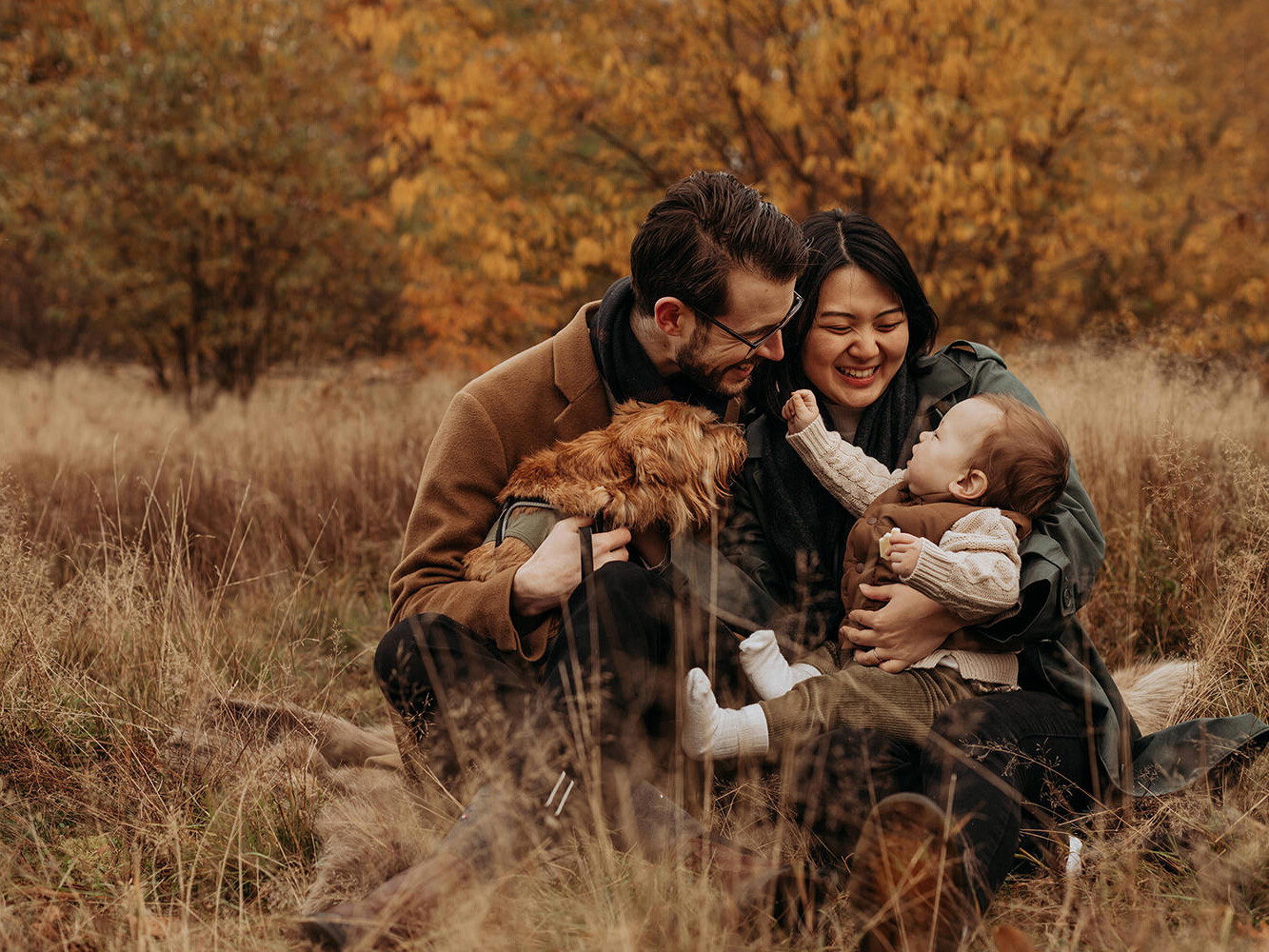 foto van een gezin met baby en hondje in een herfstsetting voor een artikel met kledingtips voor een gezinsfotoshoot