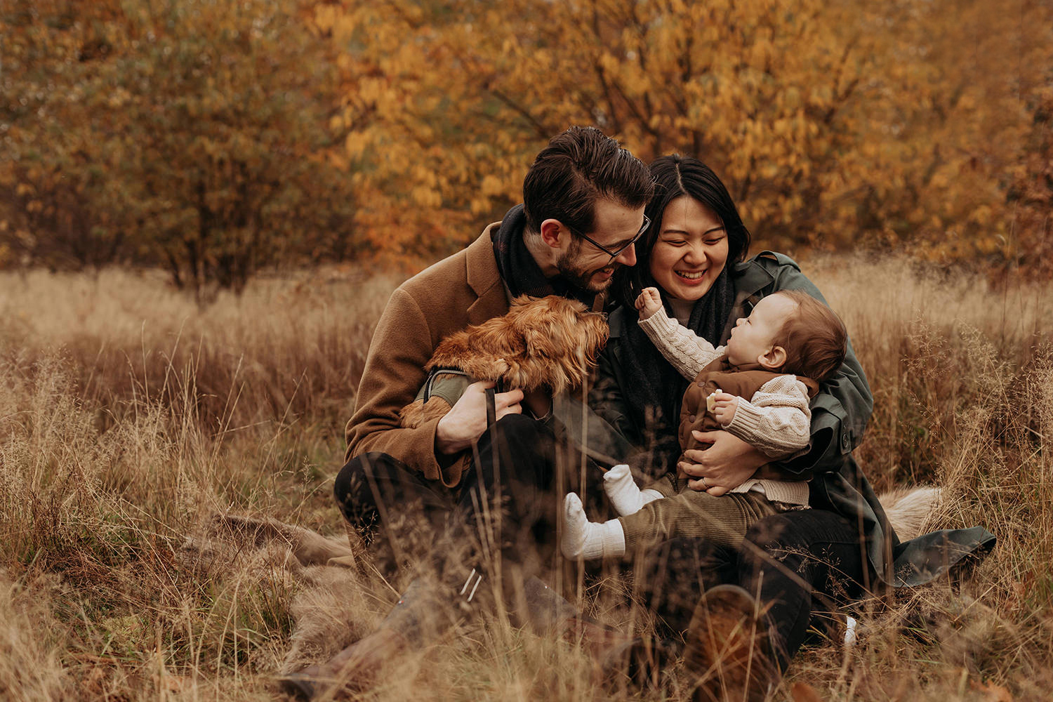 foto van een gezin met baby en hondje in een herfstsetting voor een artikel met kledingtips voor een gezinsfotoshoot