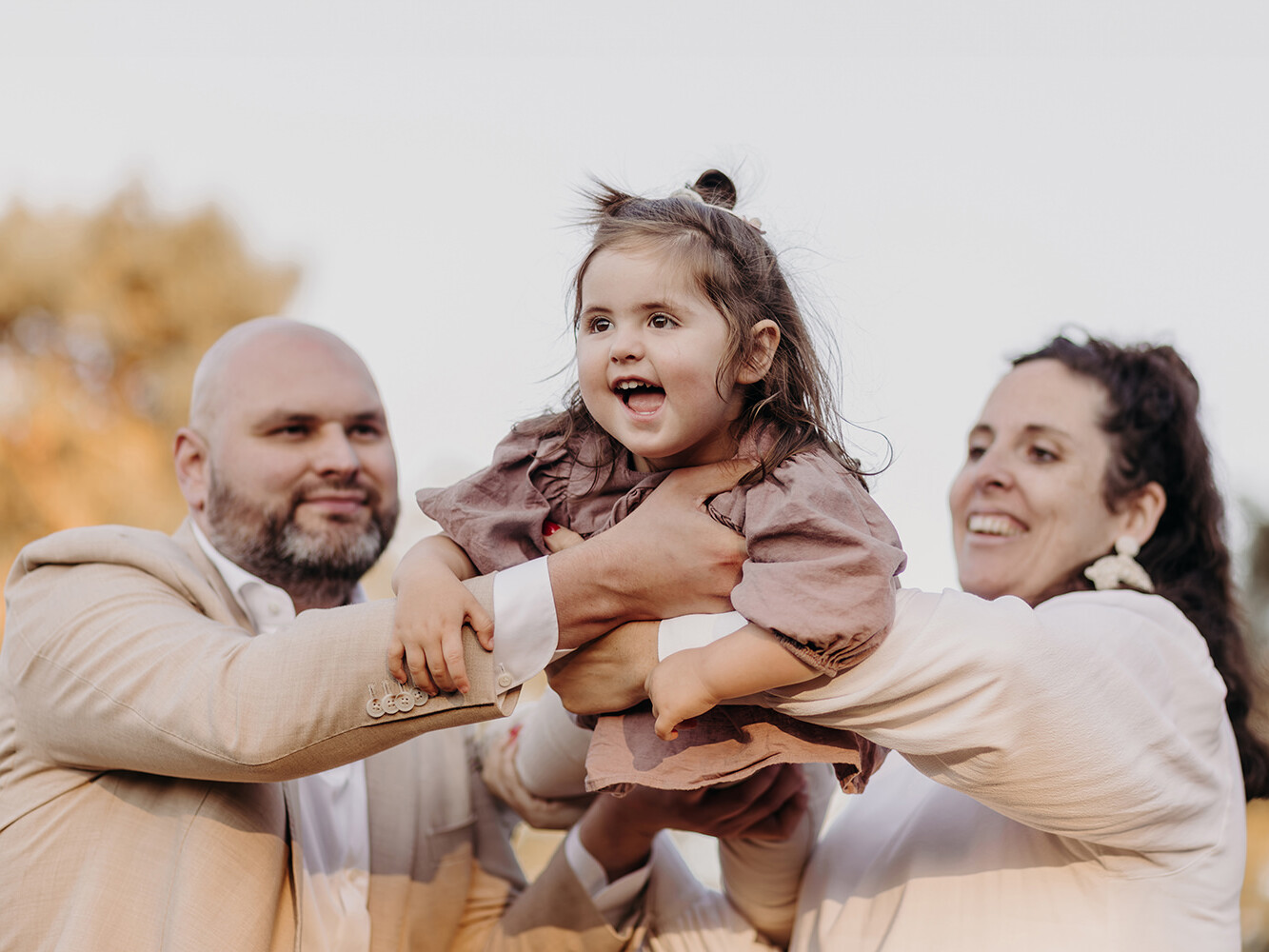 lachende meisje in de lucht met haar ouders tijdens een gezinsfotoshoot buiten