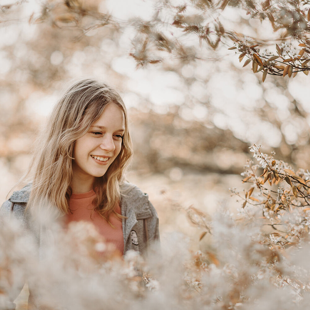 Lifestyle portret van glimlachende jonge vrouw tussen de lente bloemen