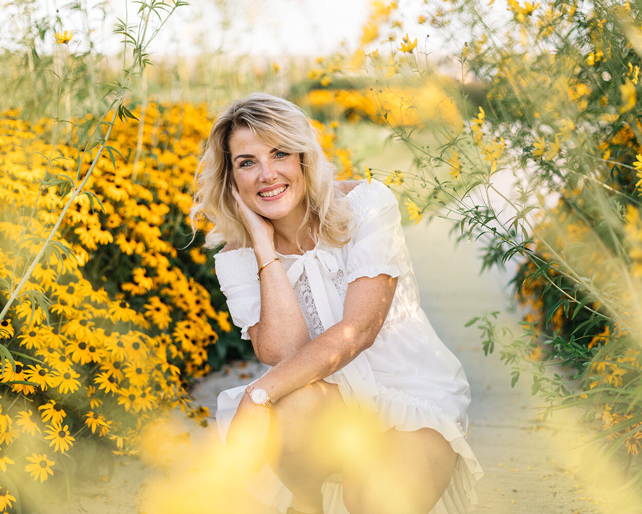 Lifestyle portret van vrouw in witte jurk in tussen gele bloemen voor personal branding