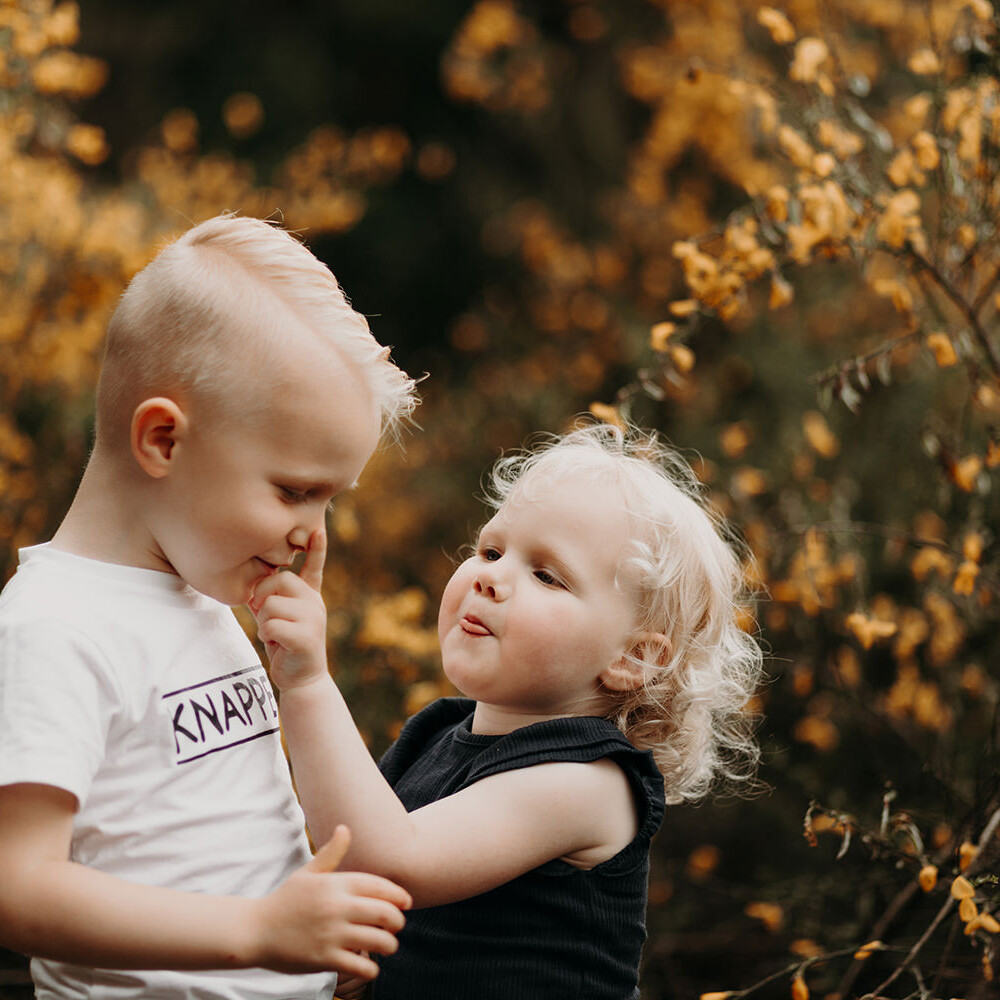 foto van broer en zusje op buiten locatie met gele bloemen op een mini fotoshoot met Picturelyspoken