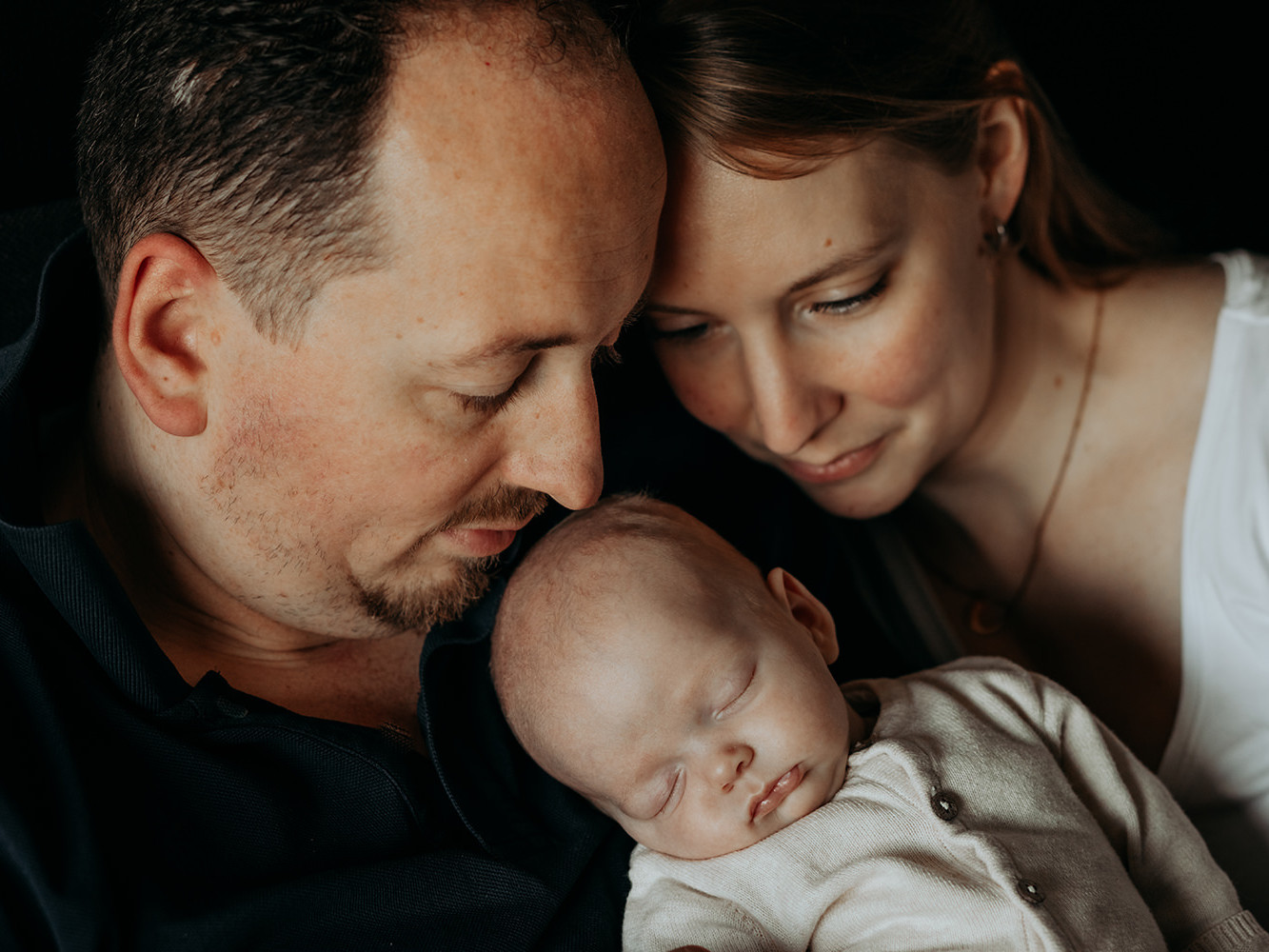 foto van een gezin van drie met een baby tijdens een gezinsfotoshoot aan huis