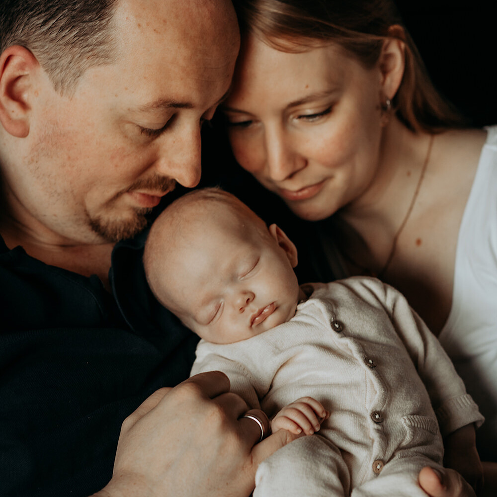 foto van een gezin van drie met een baby tijdens een gezinsfotoshoot aan huis