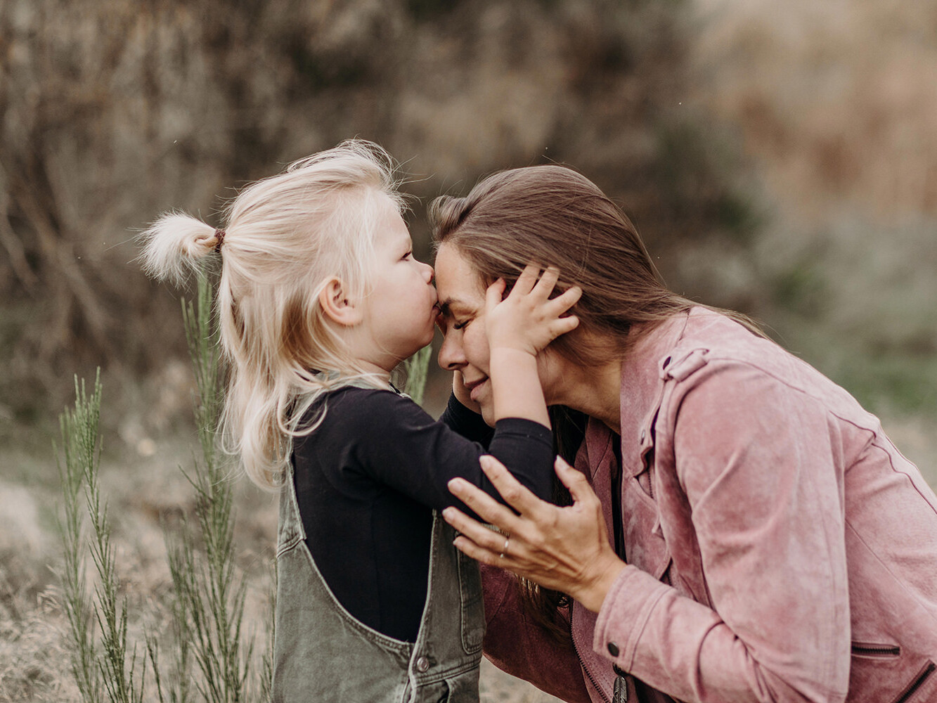 Liefdevolle foto van moeder en zoon die een kusje geeft tijdens een gezinsfotoshoot buiten in Huizen, 't Gooi