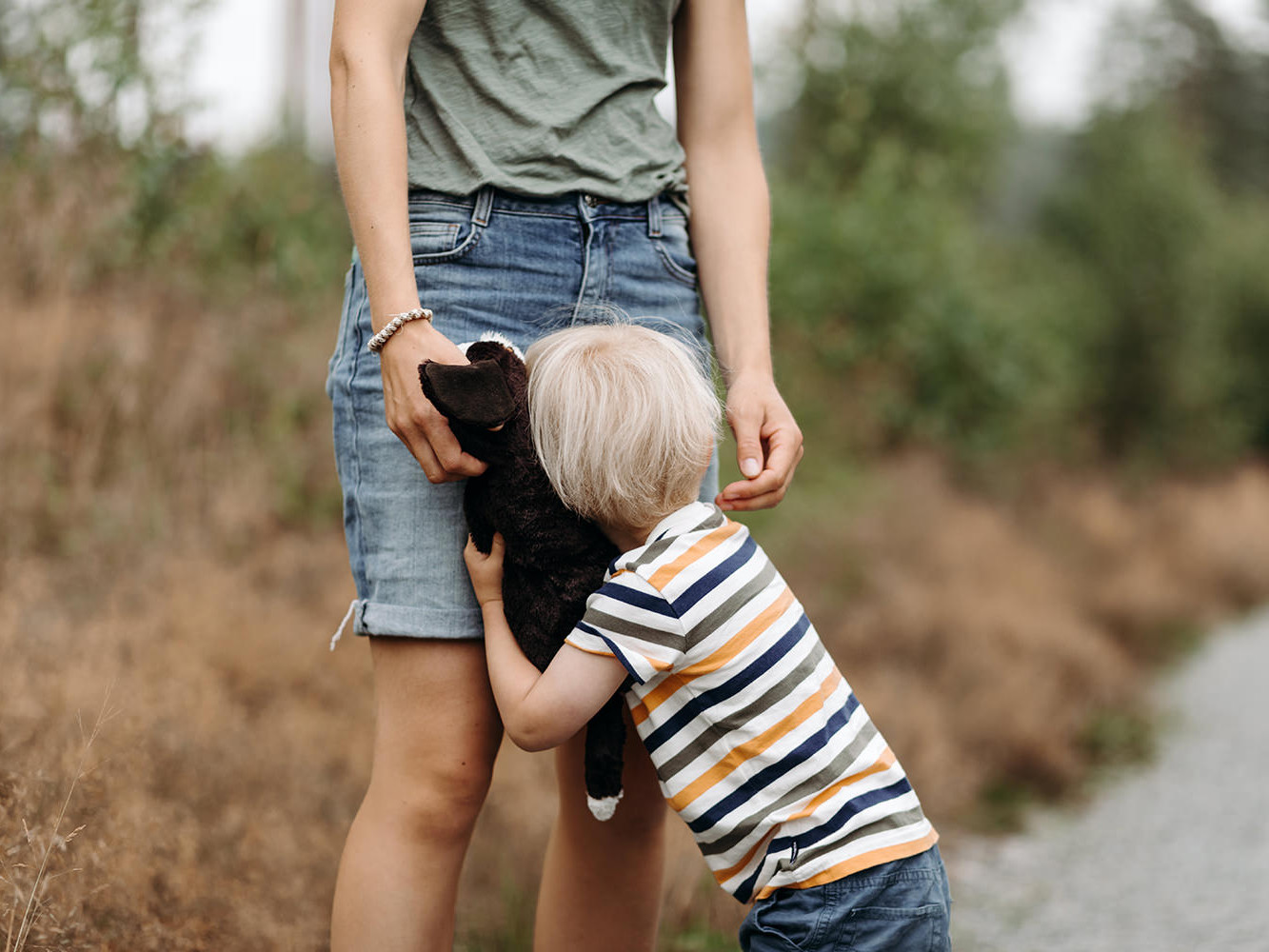 foto van een kleuter met zijn moeder en knuffel hond tijdens een gezinsfotoshoot buiten