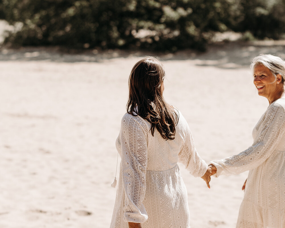 Lifestyle foto van 2 vrouwen in witte jurken in de duinen voor een personal branding fotoshoot