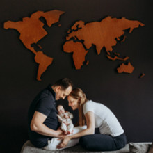 foto van een gezin met een baby en de wereldmap op de muur tijdens een gezinsfotoshoot aan huis