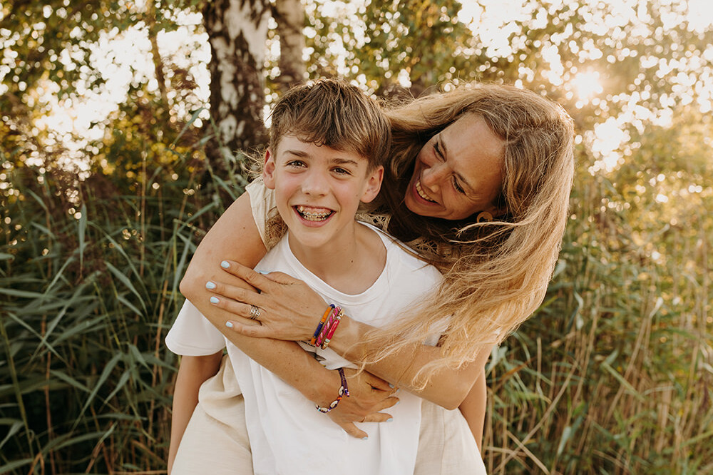 Spontane momenten die blij maken; moeder op de rug van haar zoon, allebei lachend