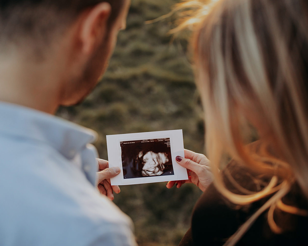 kleuren foto van een jong verliefd stel die een echo foto bekijken tijdens een zwangerschapsshoot