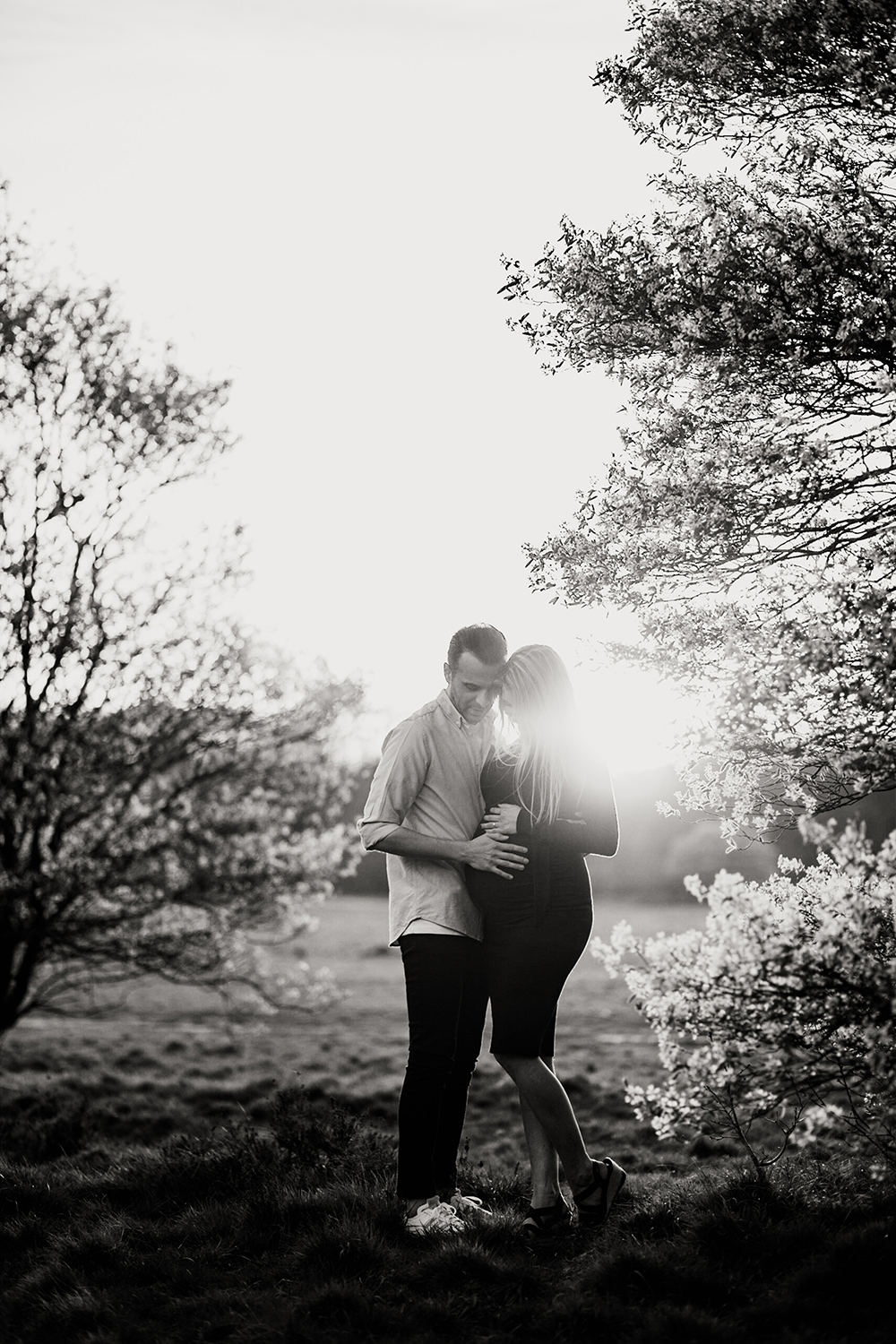 zonnige, zwart-wit foto van een jong verliefd stel tijdens een zwangerschapsshoot