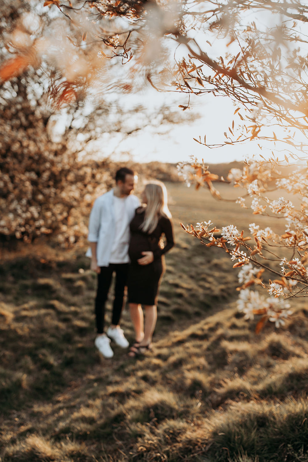 warme, zonnige foto van een jong verliefd stel tijdens een zwangerschapsshoot