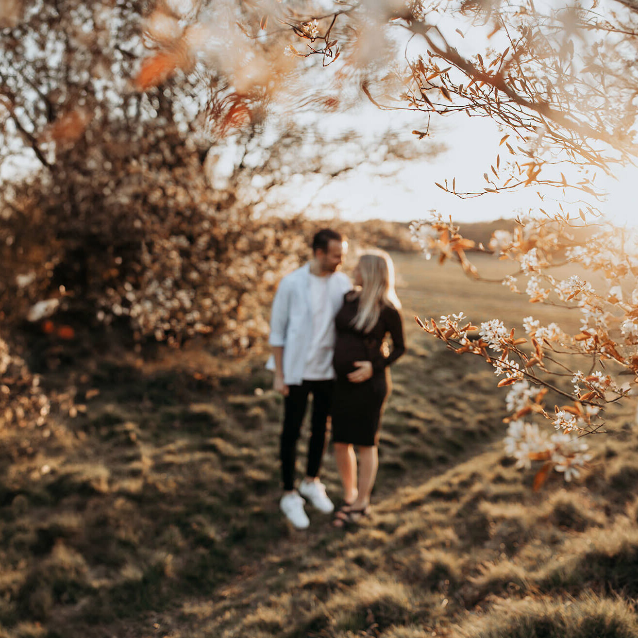 warme, zonnige foto van een jong verliefd stel tijdens een zwangerschapsshoot