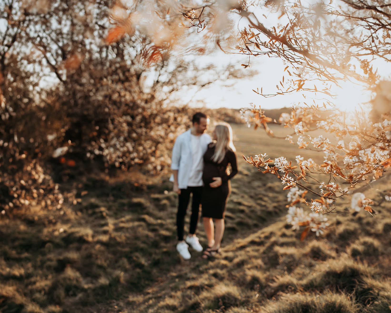 warme, zonnige foto van een jong verliefd stel tijdens een zwangerschapsshoot