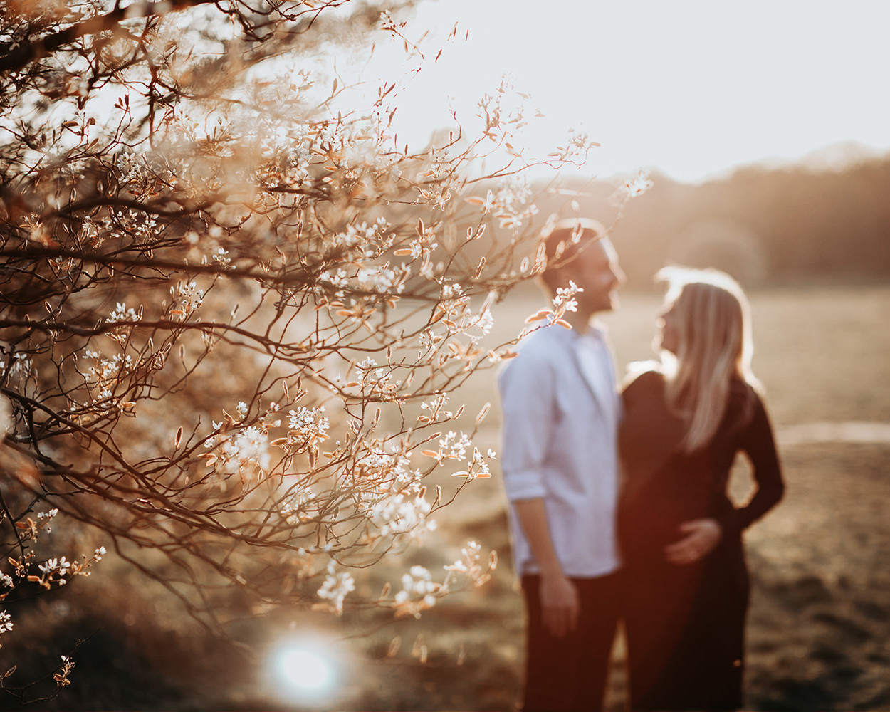 warme, zonnige foto van een jong verliefd stel tijdens een zwangerschapsshoot